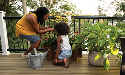 An image of a young African American mother and child looking at flowers on an outdoor deck