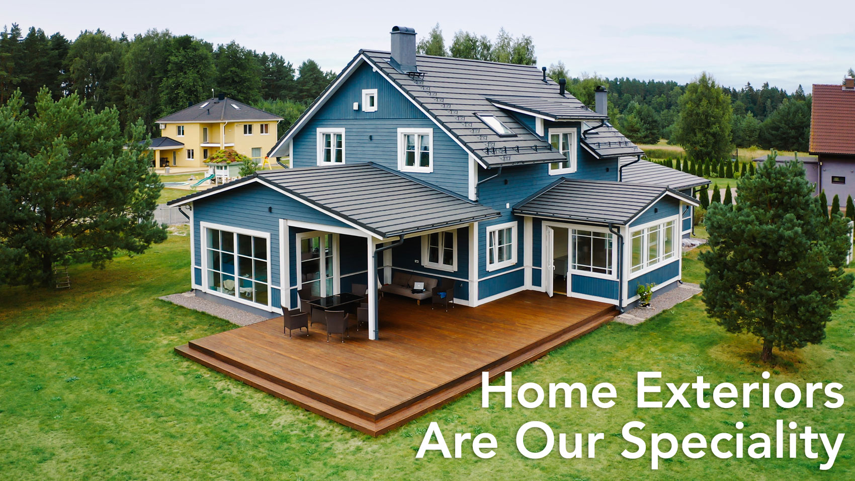 An aerial shot of a two story home with outdoor deck with the text Home Exteriors Are Our Specialty